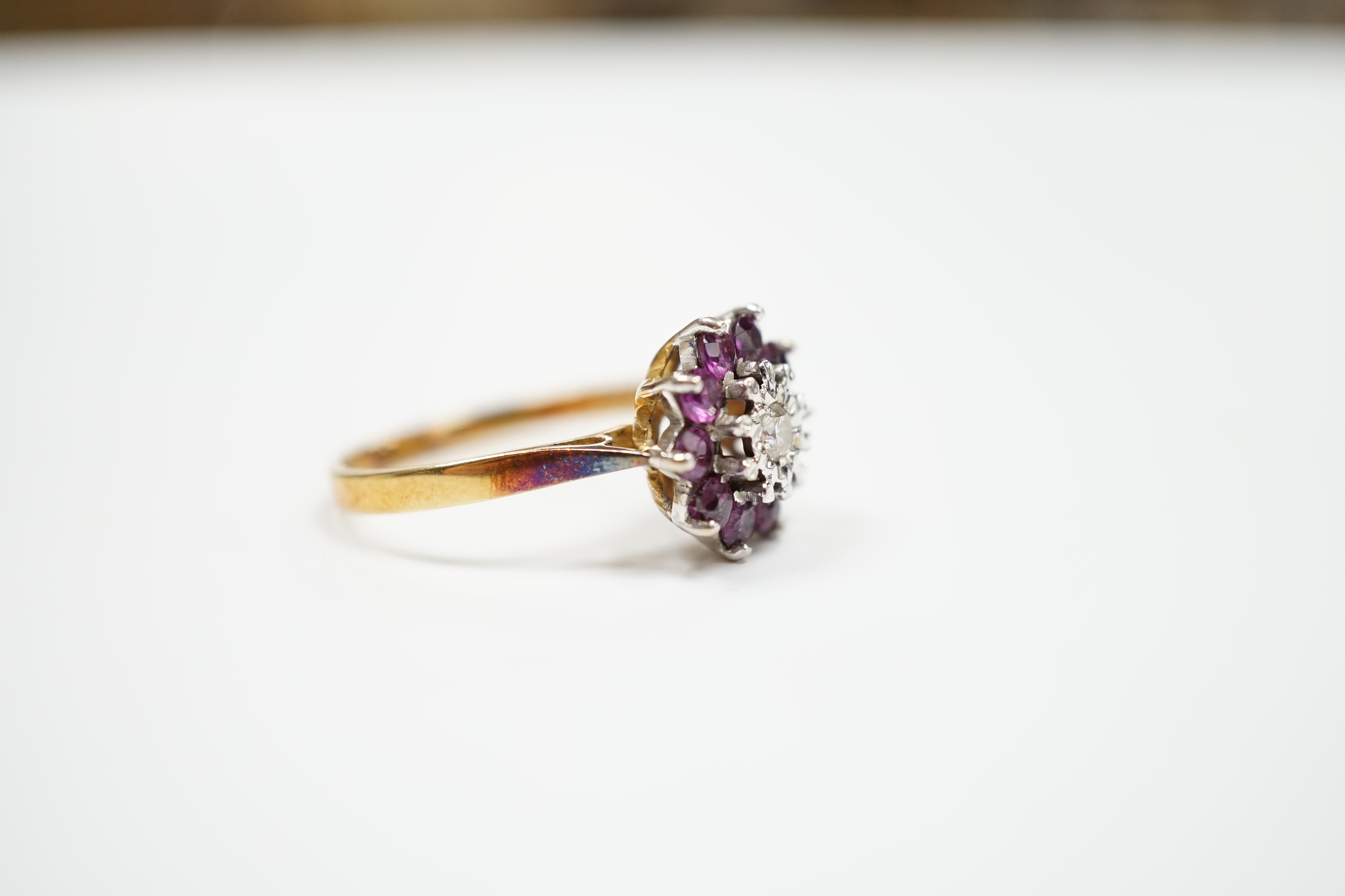 A modern 18ct gold, ruby and diamond cluster set flower head ring, size R, gross weight 4.2 grams.